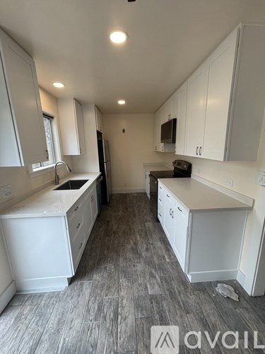 A kitchen with white cabinets and a grey floor.