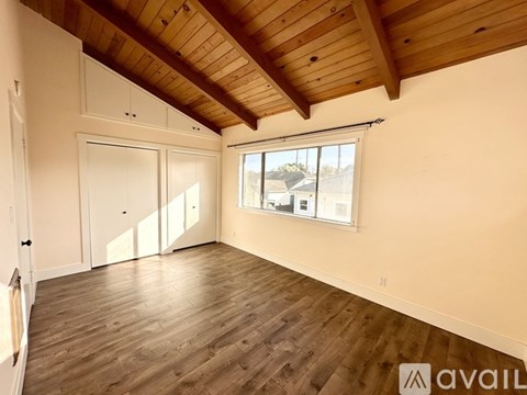 A spacious room with wooden floors and a large window.