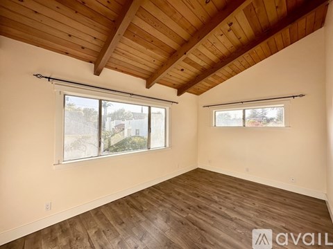 A room with wooden floors and a wooden ceiling with two windows.