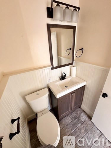 A bathroom with a toilet, sink, and mirror.