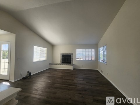 A spacious living room with a fireplace and wooden floors.