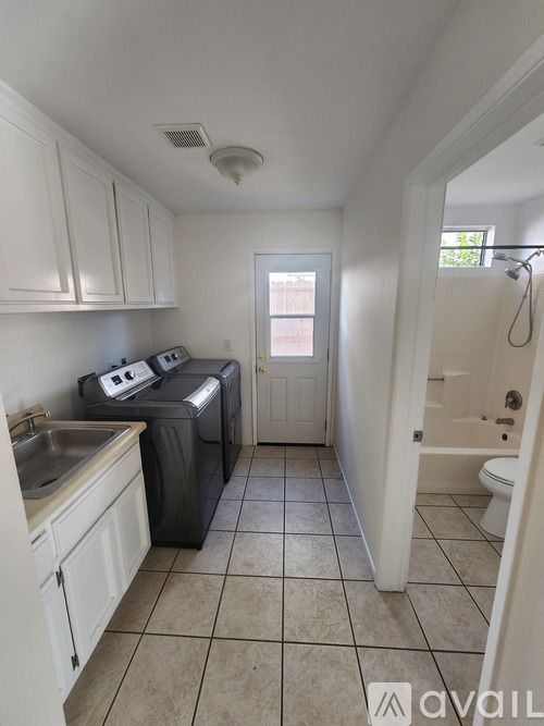 A small, clean, and well-organized kitchen with white cabinets and a tiled floor.