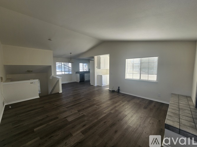A spacious room with wooden flooring and white walls.