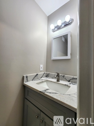 A bathroom with a marble countertop and a mirror above the sink.