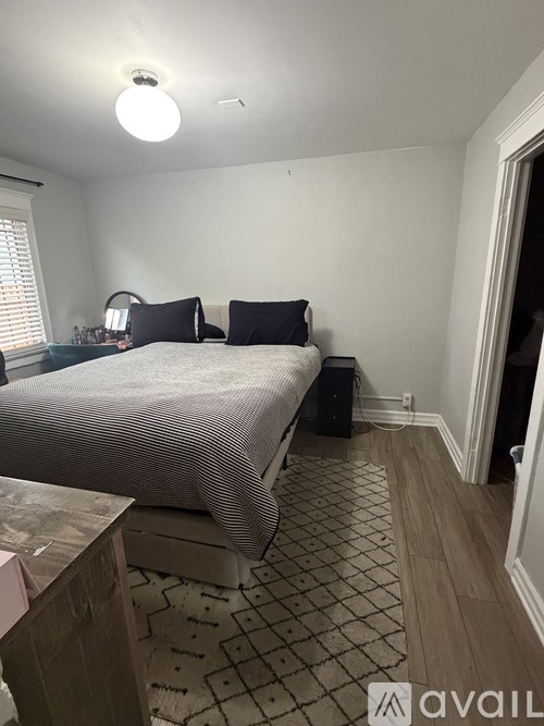 A bedroom with a bed, nightstand, and a rug.