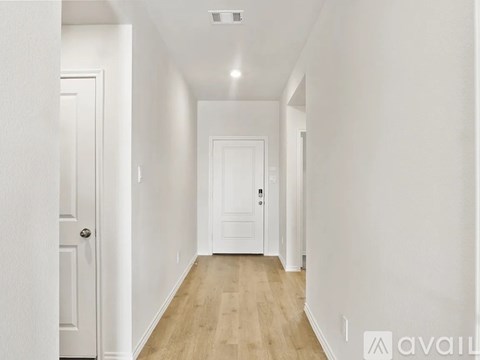 A long hallway with white walls and wood floors.