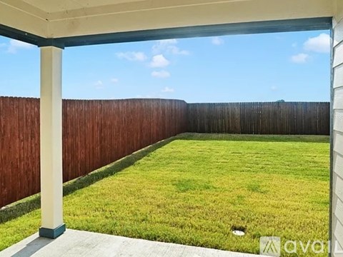 A backyard with a wooden fence and a grassy area.