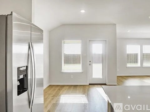 A modern kitchen with a refrigerator on the left and a dining area with a table and chairs on the right.