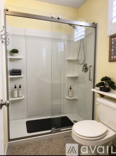A bathroom with a toilet, a glass shower stall, and a towel rack.