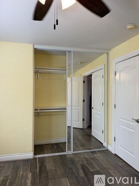 A room with a white ceiling fan and a white door.