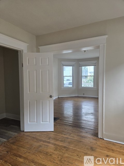 A room with a white door and wooden flooring.