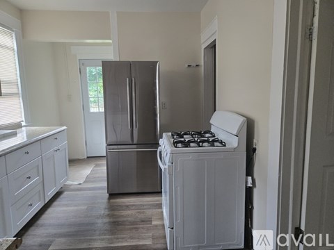 A kitchen with a stainless steel refrigerator and a white gas stove.