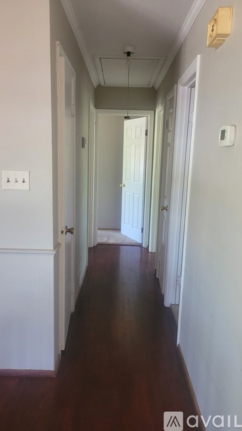 A long hallway with white walls and a wooden floor.