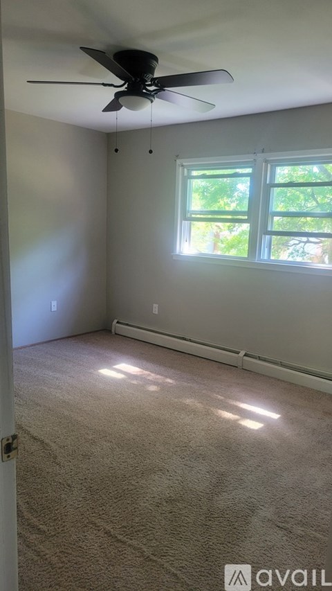 A room with a ceiling fan and a window letting in sunlight.