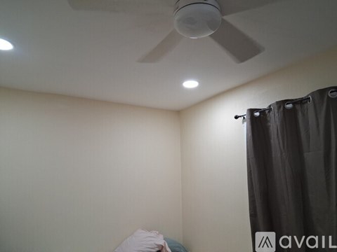 A room with a ceiling fan and a bed with a white pillow.