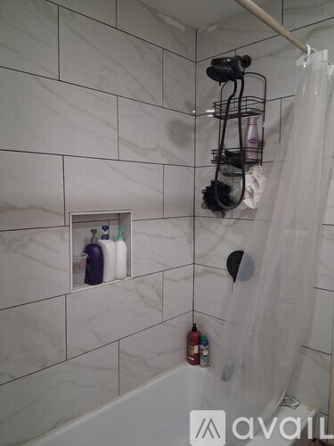 A bathroom with a white shower curtain and a white tiled wall.