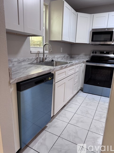 A kitchen with white cabinets and a marble countertop.