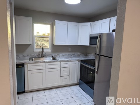 A kitchen with white cabinets and a stainless steel refrigerator.