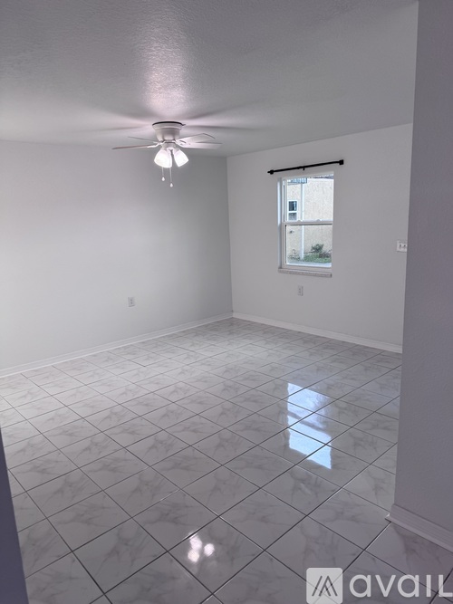 A room with a ceiling fan and a window with a view of a building outside.