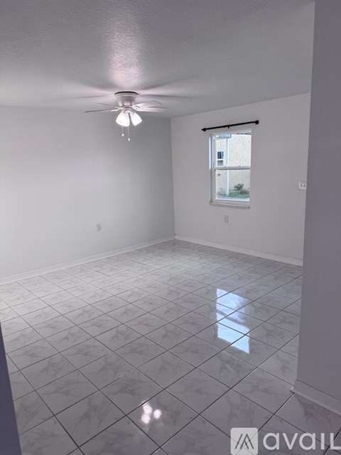 A room with a ceiling fan and a window with a view of a building outside.