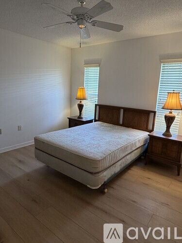 A bedroom with a bed, two lamps, and a ceiling fan.