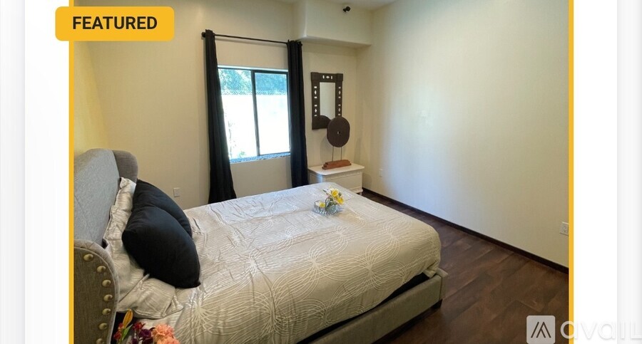 A bedroom with a bed, a chair, and a window with curtains.