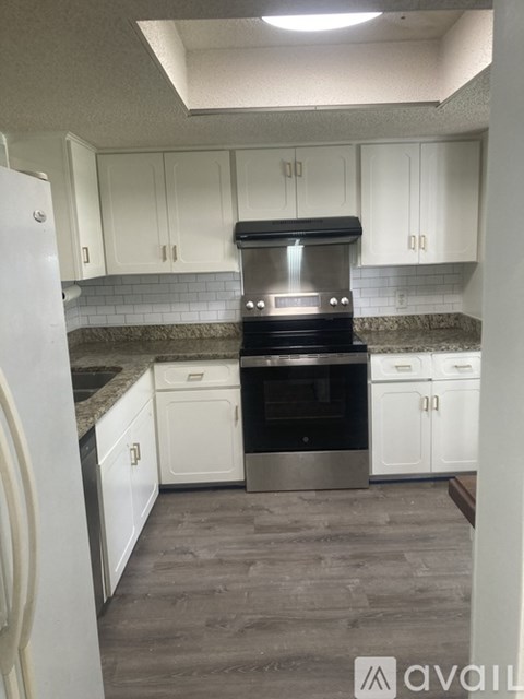 A kitchen with white cabinets and a black stove top oven.