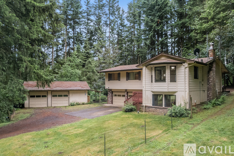 A house with a garage is surrounded by trees.