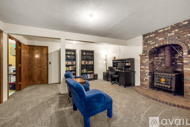 A living room with a blue chair and a fireplace.