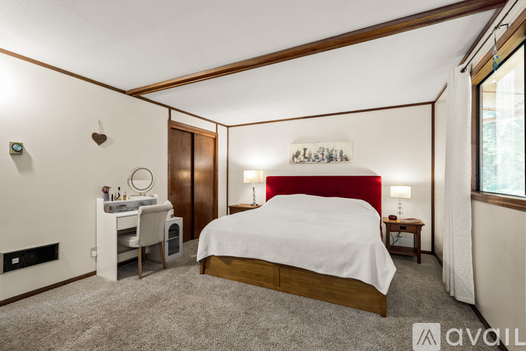 A bedroom with a red headboard and a white bedspread.