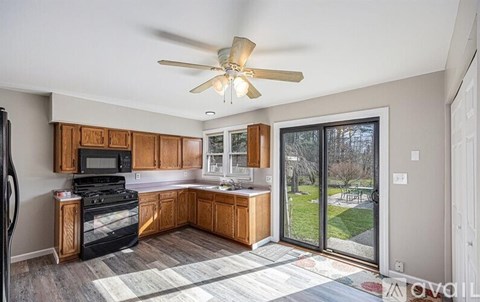 A kitchen with a black stove top oven and wooden cabinets.