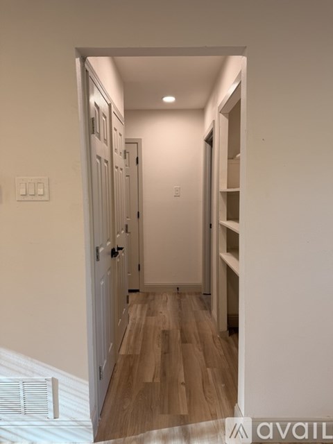 A hallway with a wooden floor and white walls.