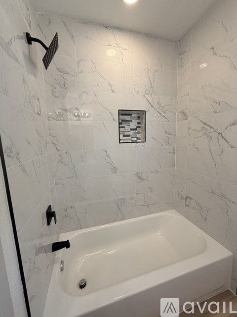 A white bathtub in a bathroom with marble tiles on the wall.