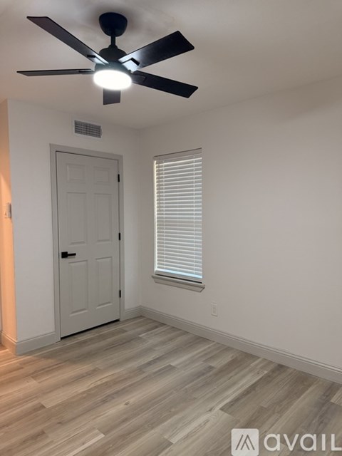 A room with a ceiling fan and a door.