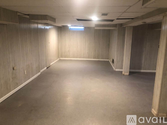 A spacious empty room with wooden walls and a concrete floor.