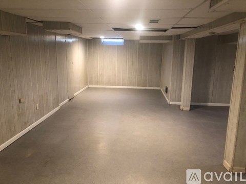A spacious empty room with wooden walls and a concrete floor.