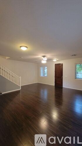 A room with wooden floors and a staircase with a railing.