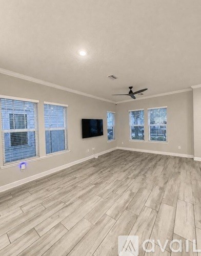 A spacious room with a television and a ceiling fan.