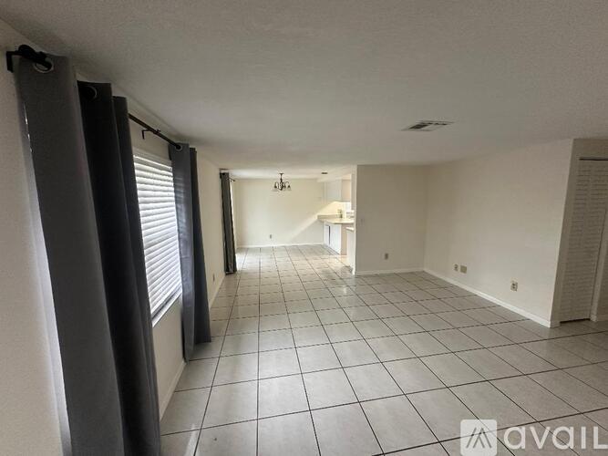 A spacious room with tiled flooring and a ceiling fan.