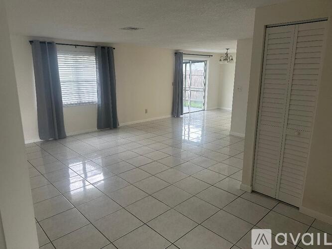 A spacious room with a tiled floor and a sliding glass door leading to a balcony.