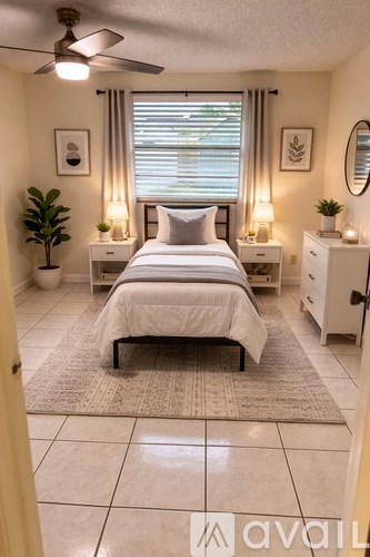 A bedroom with a bed, nightstands, and a plant.