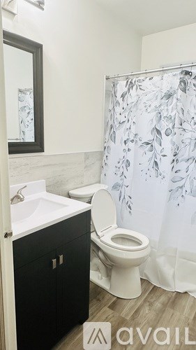A bathroom with a toilet, sink, and shower curtain.