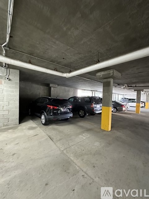 A black car is parked in a concrete parking garage.