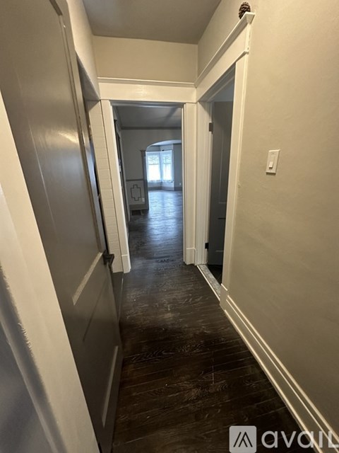 A hallway with a wooden floor and white walls.