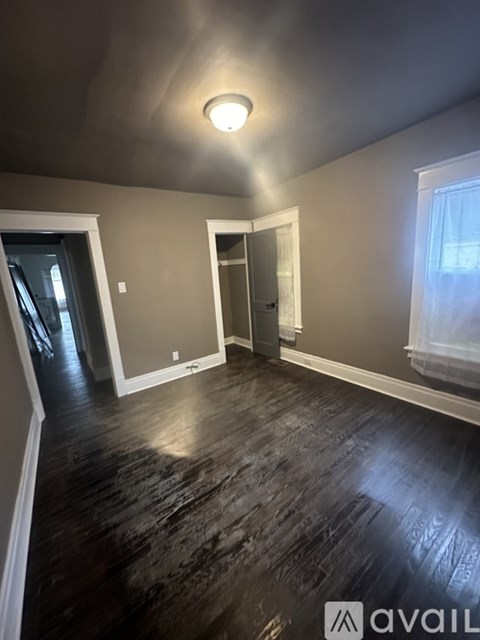 A room with dark wood flooring and a single light fixture on the ceiling.