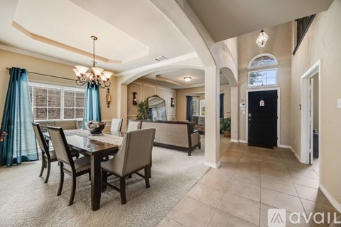 A dining room with a table set for six with a chandelier hanging above.