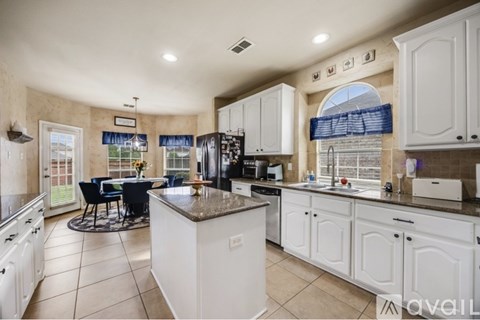 A kitchen with white cabinets and a large island.