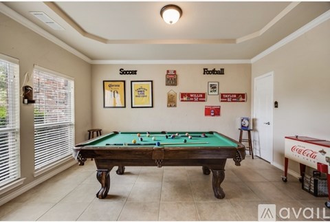 A pool table in a room with a soccer and football poster on the wall.