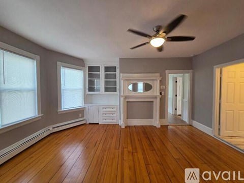 A room with a ceiling fan and wooden floors.