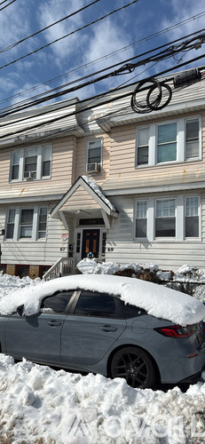A car covered in snow is parked in front of a house.